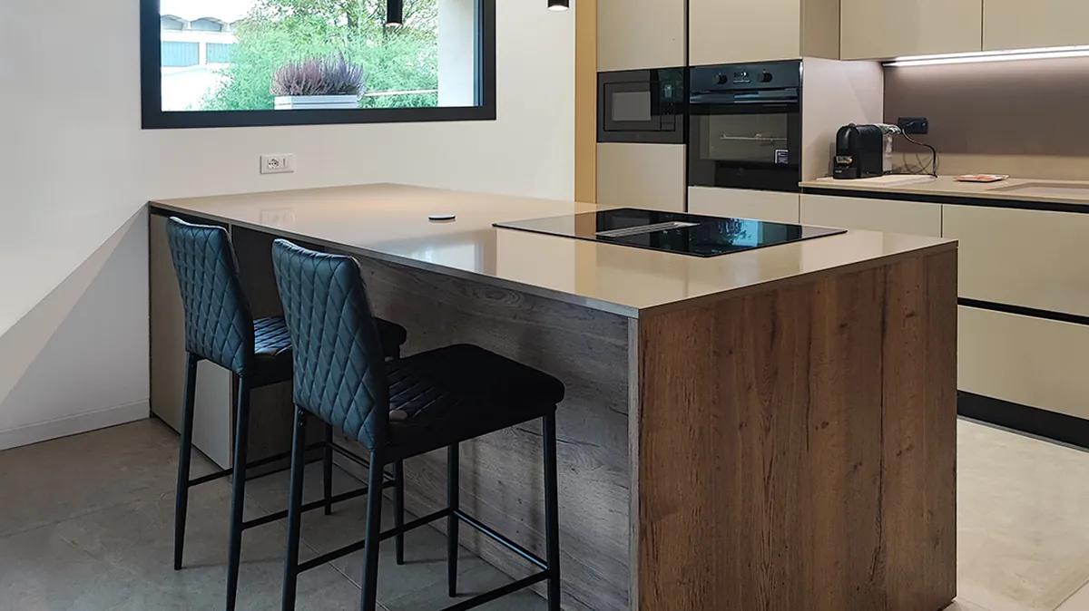 Cucina con isola e piano a induzione realizzata da Ruffato Arredamenti, con sgabelli, colonne forno e finestra sul giardino